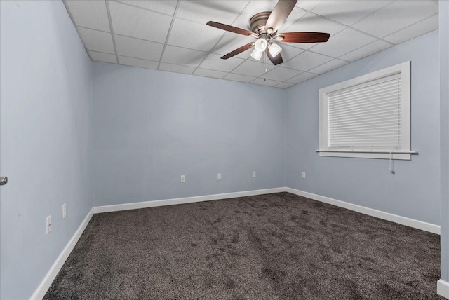 empty room featuring baseboards, dark colored carpet, a drop ceiling, and ceiling fan