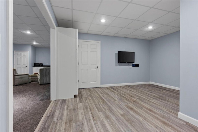 unfurnished living room featuring recessed lighting, wood finished floors, baseboards, and a paneled ceiling