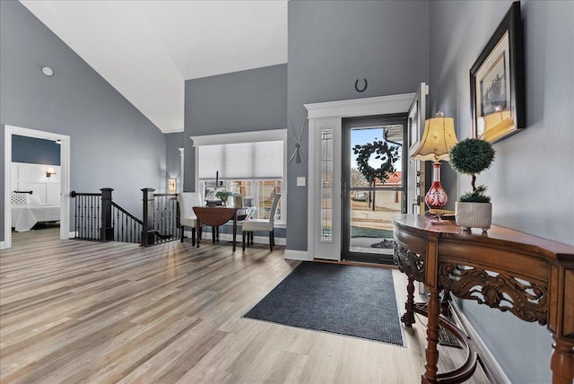 entryway with baseboards, high vaulted ceiling, and light wood-style flooring