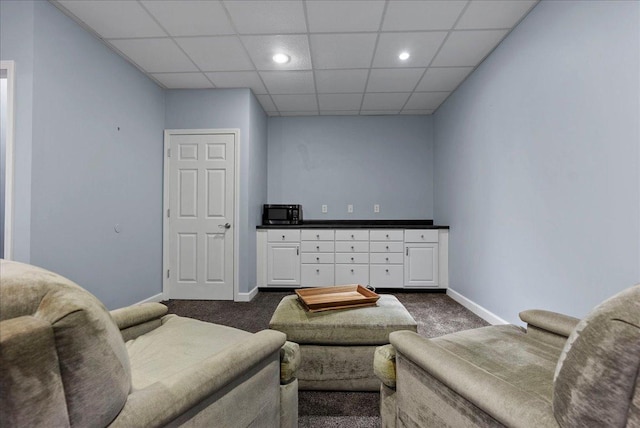 living room with dark colored carpet, a paneled ceiling, baseboards, and recessed lighting