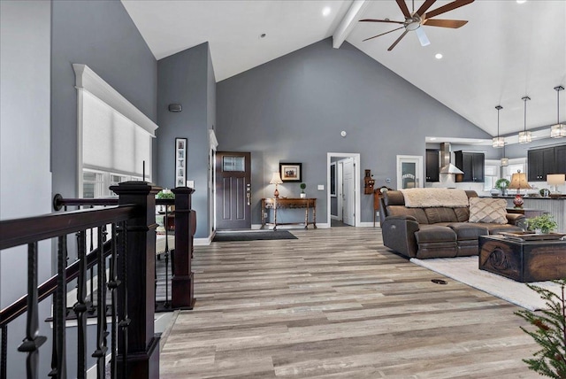 living room featuring baseboards, beamed ceiling, light wood-style flooring, high vaulted ceiling, and a ceiling fan