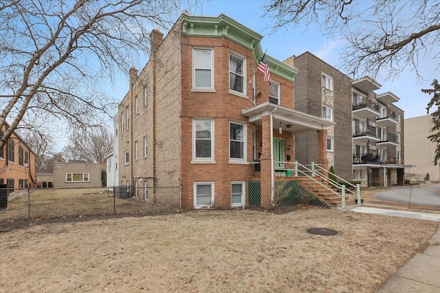 view of front of home featuring brick siding, central air condition unit, a chimney, and fence