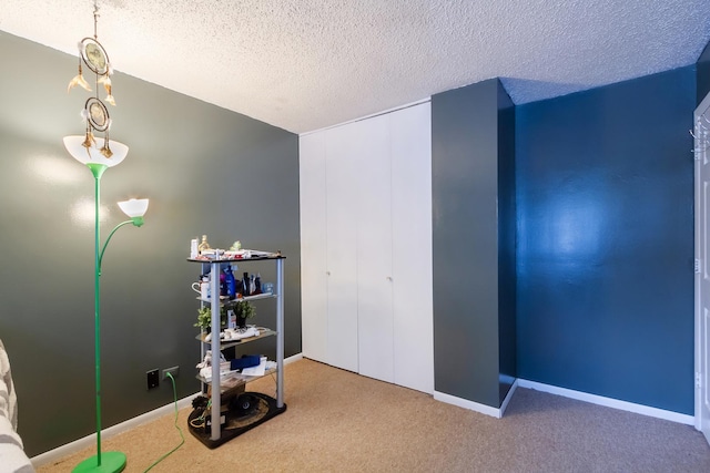 carpeted bedroom with a closet, baseboards, and a textured ceiling