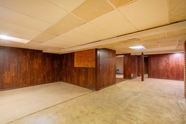 finished below grade area featuring wood walls and a paneled ceiling