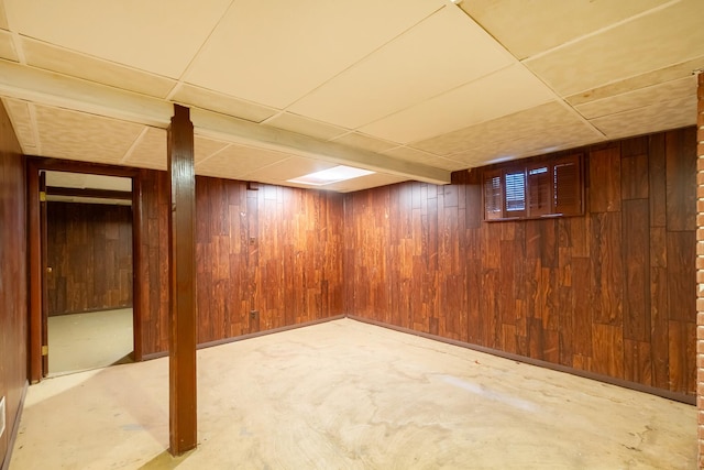 finished below grade area featuring wood walls and a paneled ceiling