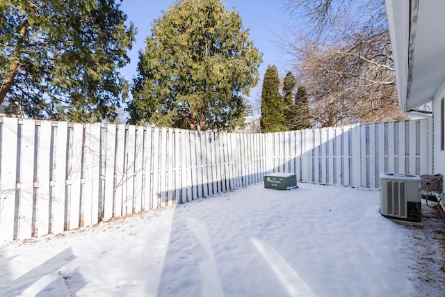 yard layered in snow featuring central AC and a fenced backyard