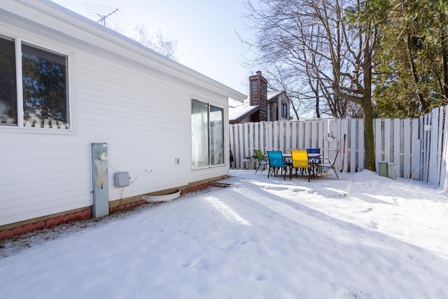 snow covered patio with outdoor dining space and fence