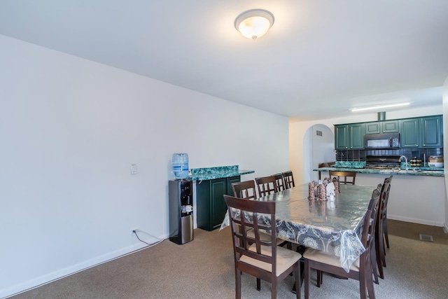 dining area featuring arched walkways, baseboards, visible vents, and carpet