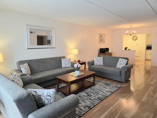 living area featuring a notable chandelier, a textured ceiling, visible vents, and wood finished floors