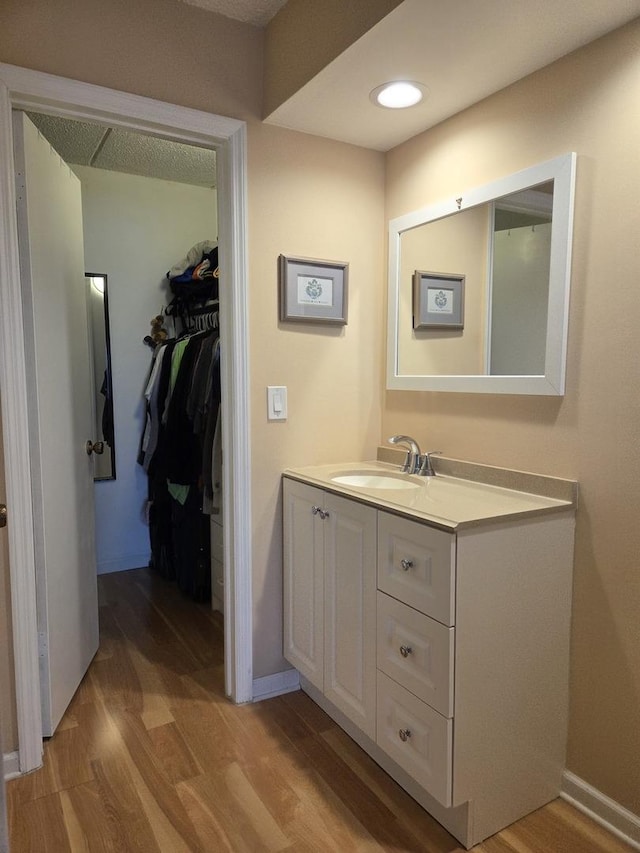 bathroom featuring recessed lighting, wood finished floors, vanity, and baseboards