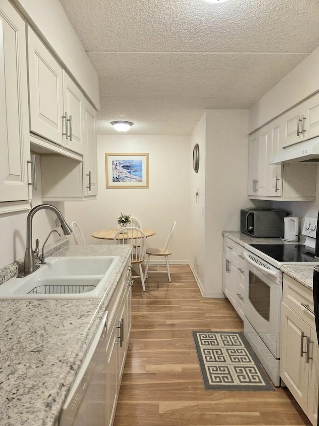 kitchen with white electric range oven, light wood-style floors, dishwasher, under cabinet range hood, and a sink