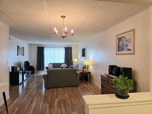 living room featuring a chandelier, dark wood-style flooring, a textured ceiling, and baseboards