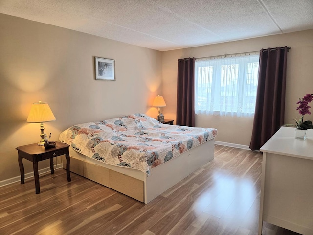 bedroom featuring a textured ceiling, baseboards, and wood finished floors