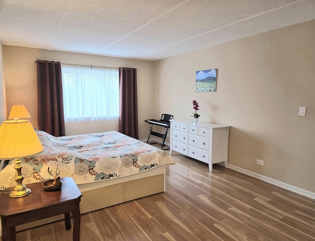 bedroom with a textured ceiling, wood finished floors, and baseboards