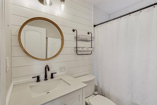 bathroom with curtained shower, wooden walls, toilet, and vanity