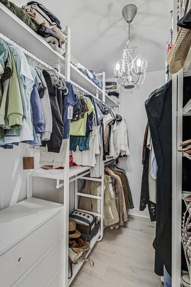 spacious closet with light wood-style floors and a chandelier