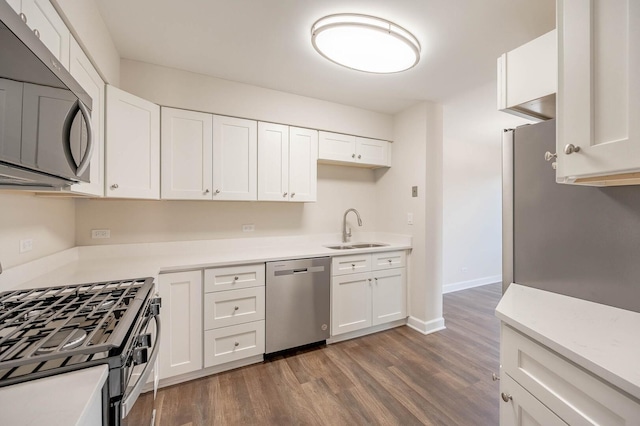 kitchen featuring a sink, wood finished floors, white cabinetry, appliances with stainless steel finishes, and light countertops