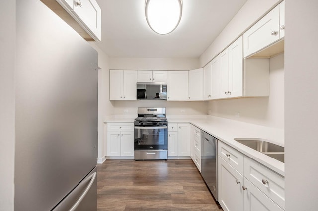 kitchen featuring a sink, light countertops, white cabinets, stainless steel appliances, and dark wood-style flooring