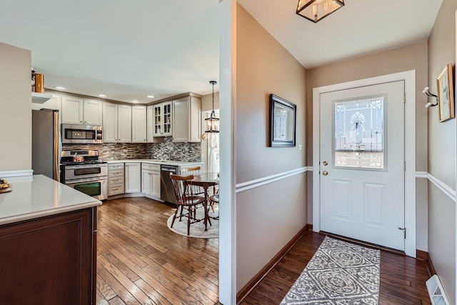 kitchen featuring dark wood-type flooring, visible vents, light countertops, appliances with stainless steel finishes, and decorative backsplash