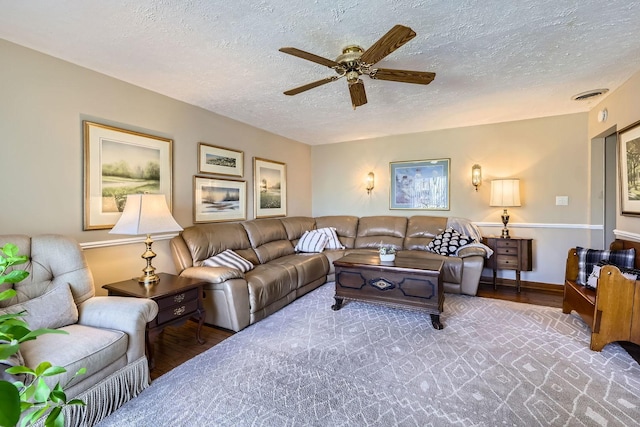 living area featuring ceiling fan, a textured ceiling, visible vents, and wood finished floors