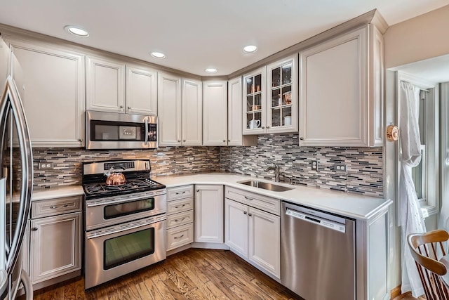 kitchen with light countertops, appliances with stainless steel finishes, a sink, and light wood-style floors