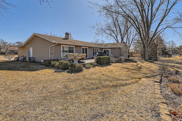 back of property with central AC, a chimney, a patio, and a lawn