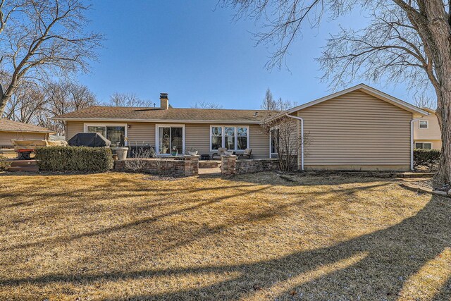 rear view of property featuring a chimney, a patio, and a yard