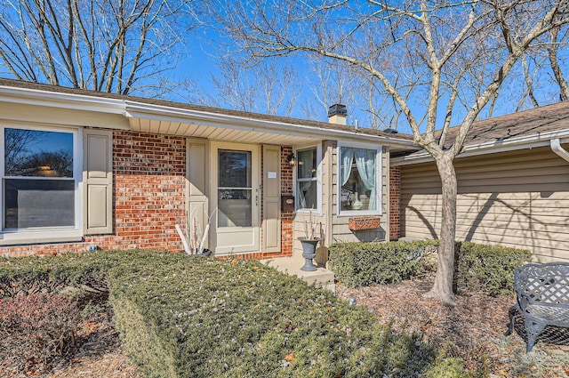 doorway to property featuring brick siding and a chimney