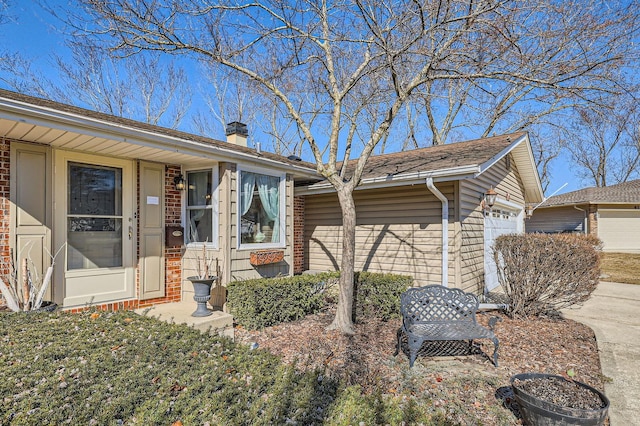 single story home with a garage, brick siding, and a chimney