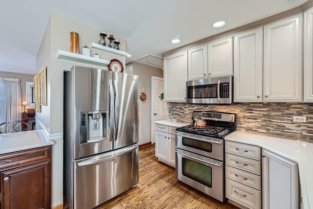 kitchen featuring stainless steel appliances, recessed lighting, light countertops, light wood-style flooring, and decorative backsplash