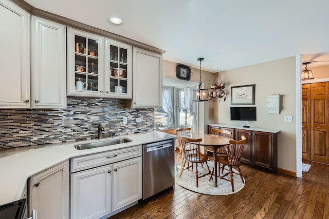 kitchen with a sink, light countertops, backsplash, dishwasher, and decorative light fixtures