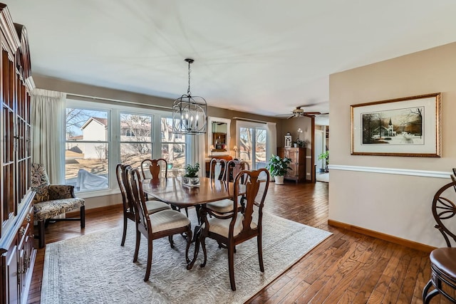 dining room with ceiling fan with notable chandelier, hardwood / wood-style floors, and baseboards