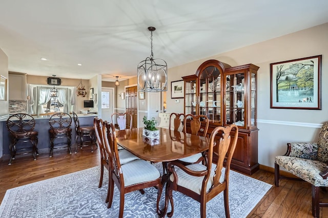 dining room featuring wood-type flooring, baseboards, and a chandelier