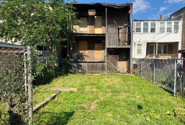 back of property with fence and a lawn