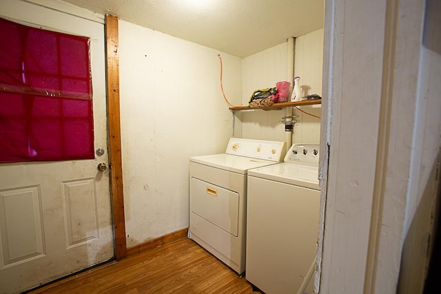 clothes washing area with laundry area, light wood finished floors, and washer and clothes dryer