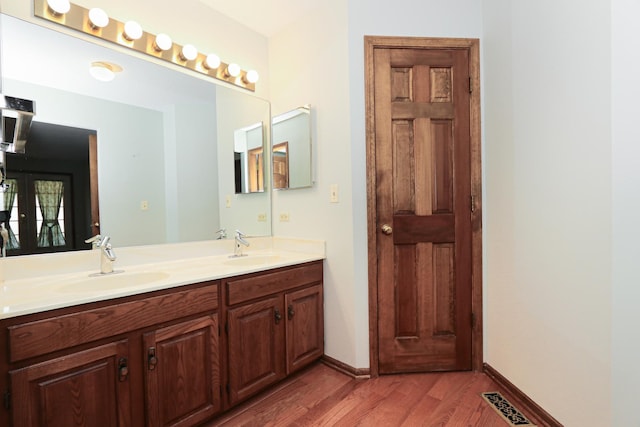 full bath with a sink, visible vents, double vanity, and wood finished floors