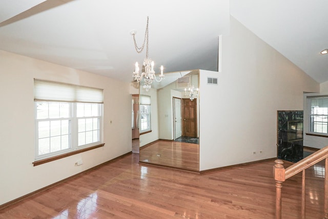 interior space featuring a healthy amount of sunlight, visible vents, an inviting chandelier, and wood finished floors