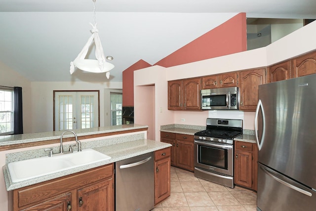 kitchen with appliances with stainless steel finishes, light tile patterned floors, light countertops, lofted ceiling, and a sink