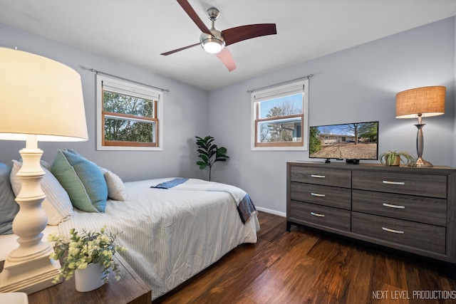 bedroom featuring multiple windows, a ceiling fan, baseboards, and dark wood-style flooring