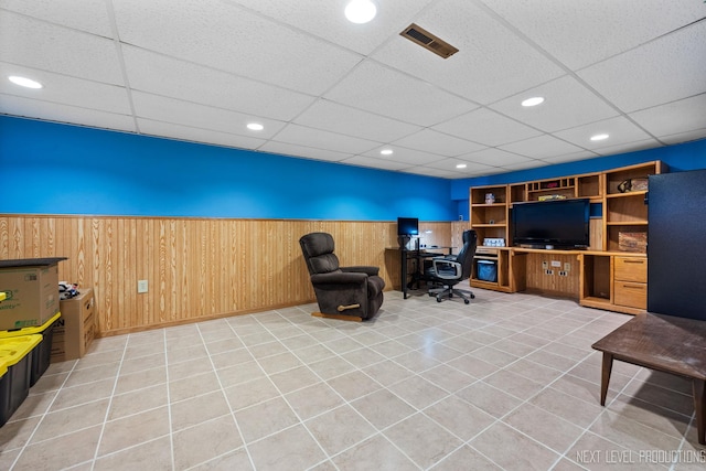 home office with light tile patterned floors, visible vents, wood walls, and wainscoting