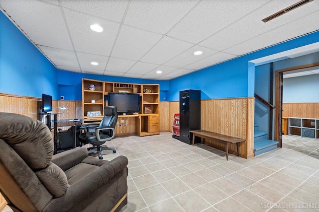 home office with visible vents, a paneled ceiling, a wainscoted wall, and light tile patterned flooring