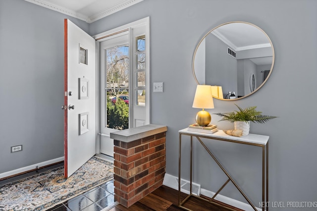 foyer entrance with crown molding, wood finished floors, baseboards, and visible vents