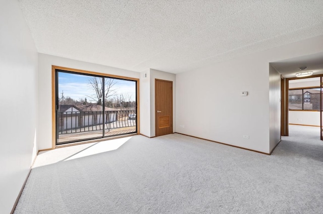 spare room featuring a textured ceiling, carpet flooring, and baseboards