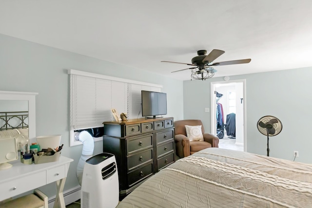 bedroom featuring a baseboard heating unit, a walk in closet, and ceiling fan