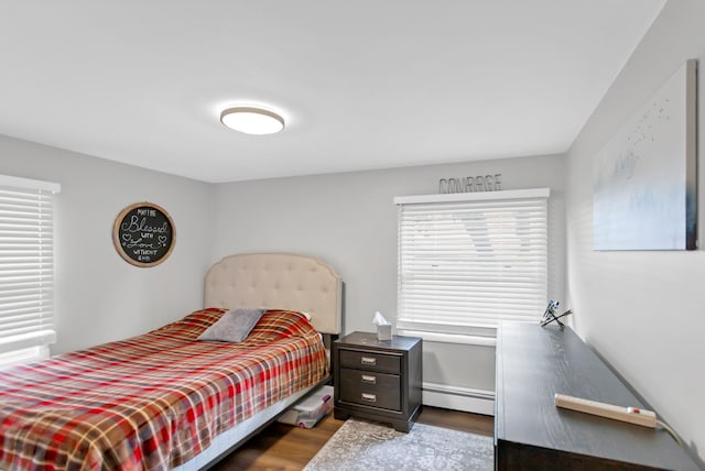 bedroom featuring a baseboard heating unit and wood finished floors