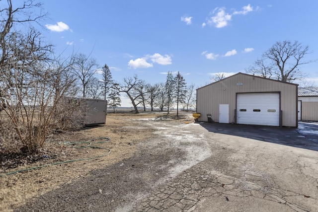 exterior space featuring driveway, a detached garage, and an outdoor structure