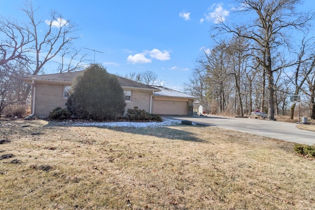 view of property exterior with concrete driveway, brick siding, a lawn, and an attached garage