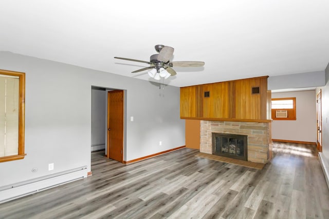 unfurnished living room with baseboards, a fireplace with flush hearth, baseboard heating, light wood-style floors, and a baseboard heating unit