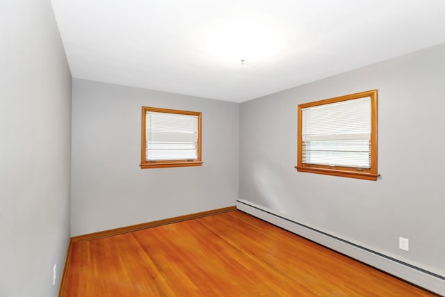 spare room featuring baseboard heating, wood finished floors, and baseboards