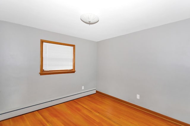 unfurnished room with baseboards, light wood-style flooring, and baseboard heating